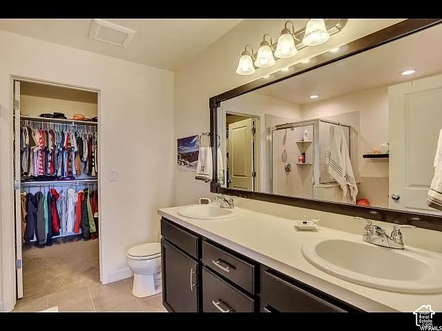 Bathroom featuring a dual vanity with dark cabinetry and a light-colored countertop
