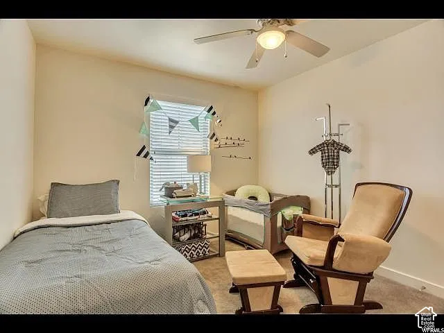 Carpeted room featuring a ceiling fan with integrated lighting, a window with horizontal blinds, and neutral wall tones