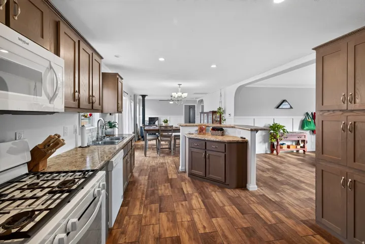Kitchen featuring wood-finish flooring, built-in cabinetry, a gas range, a double basin sink, and an integrated microwave
