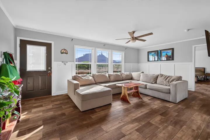 Living area featuring wood-finish flooring, white wainscoting, and light gray walls