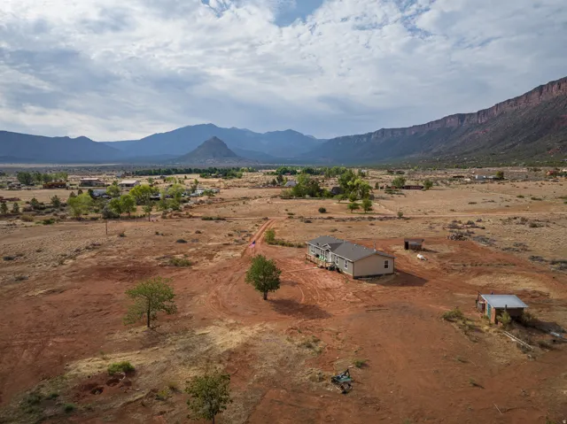 Expansive property featuring a single-story residence with a covered porch and light-toned siding, situated on a substantial parcel of land