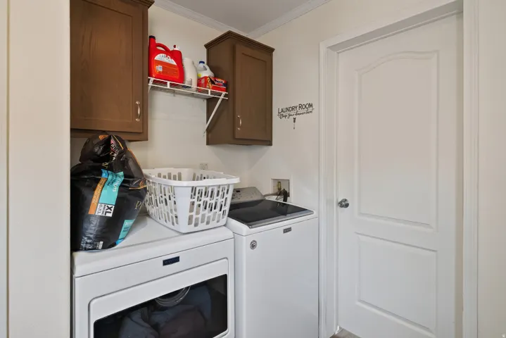 Dedicated laundry area featuring upper cabinetry, a wall-mounted wire shelf, and a panel door with a round knob