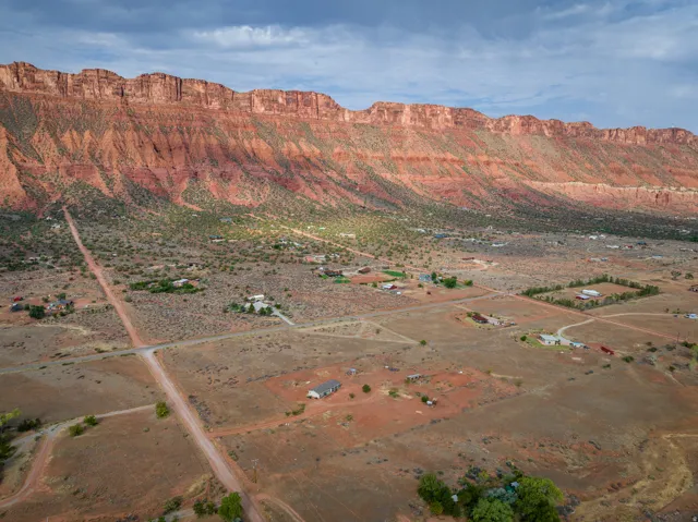Expansive desert landscape featuring a prominent red rock cliff formation