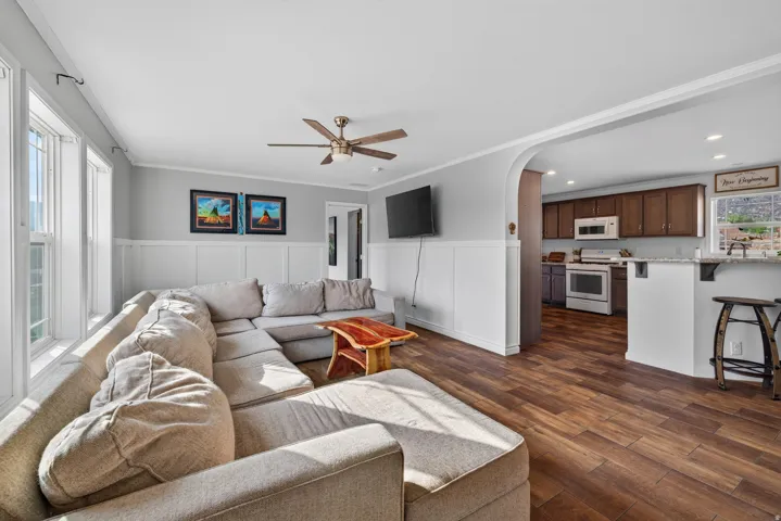 Spacious living area featuring wood-finish flooring, wainscoting, and a ceiling fan