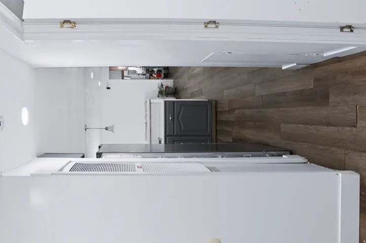 Kitchen featuring wood-finish flooring, dark grey cabinetry, white countertops, and a built-in range hood