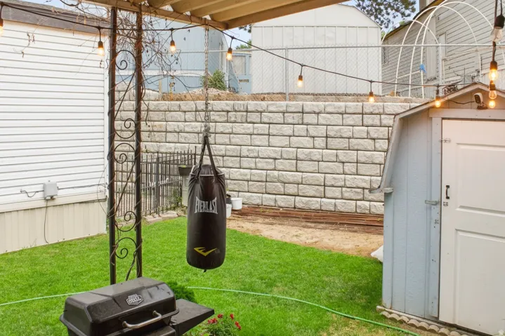 Backyard space featuring a retaining wall, manicured lawn, and string lighting