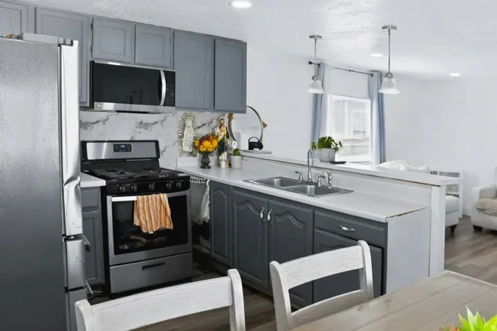 Kitchen featuring stainless steel appliances, grey cabinetry, white countertops, a double basin sink, and wood-finish flooring
