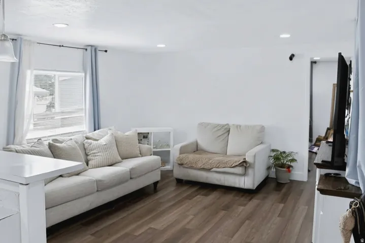 Bright living area featuring wood-finish flooring, recessed lighting, and a white accent wall