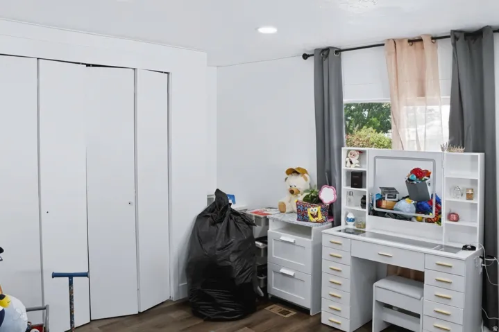 Interior room featuring wood-finish flooring, white walls, and bi-fold closet doors