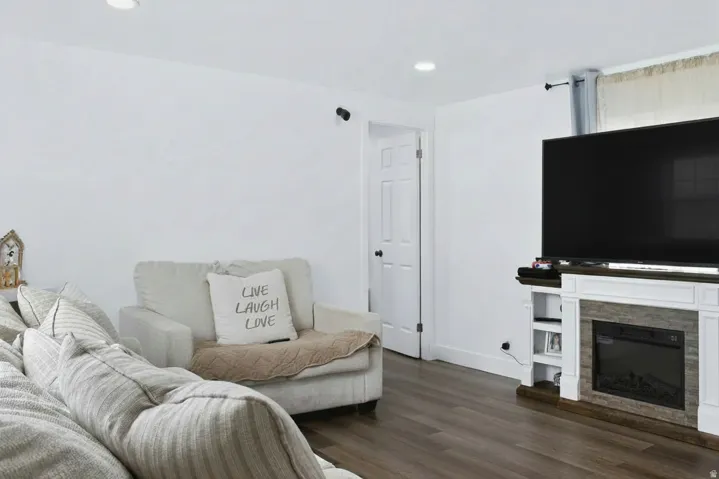 Living area featuring wood-finish flooring, white walls, recessed lighting, and a built-in media console with an electric fireplace