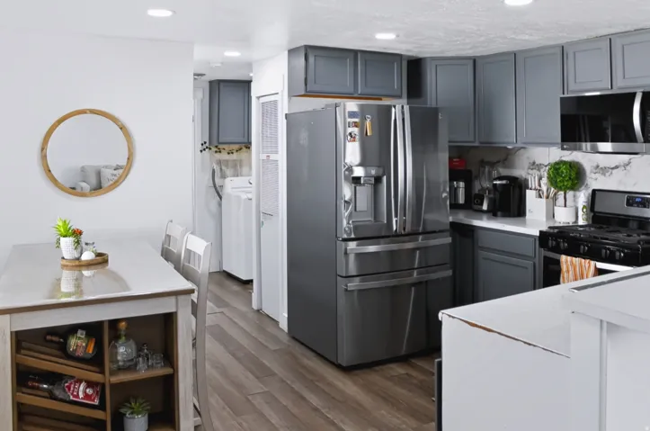 Kitchen featuring contemporary gray cabinetry, stainless steel appliances, white countertops, and a patterned backsplash