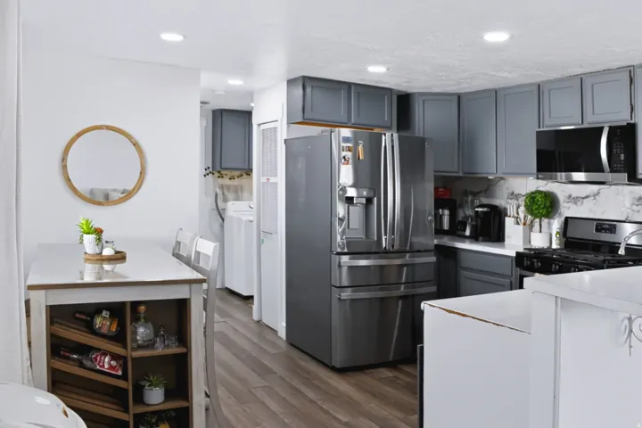 Kitchen featuring gray cabinetry, stainless steel appliances, white countertops, and a marble-finish backsplash