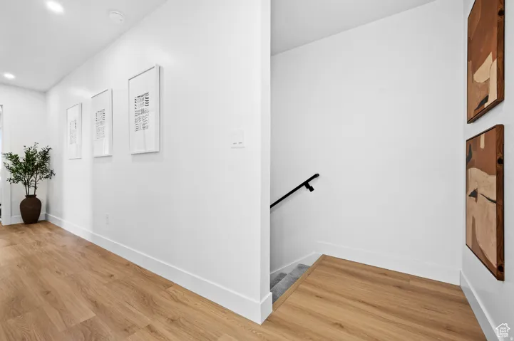 Hallway featuring wood-finish flooring, recessed lighting, and crisp white walls