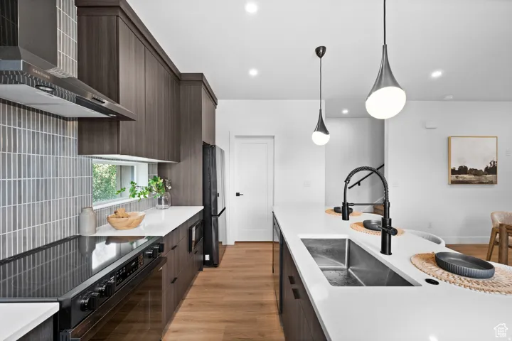 Modern kitchen featuring dark wood-finish cabinetry, light stone countertops, integrated stainless steel appliances, and wood-finish flooring