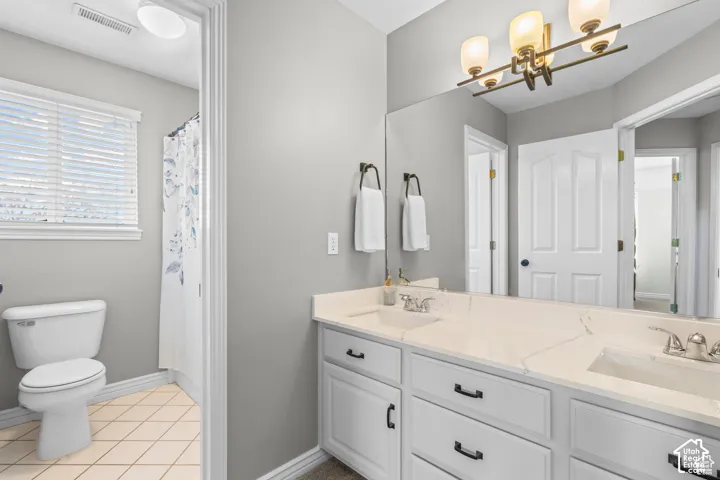 Double vanity with white cabinetry, light-toned countertops, and a full-width mirror