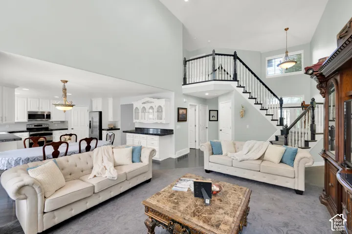 Vaulted living area featuring a prominent staircase with dark wood handrails and white balusters