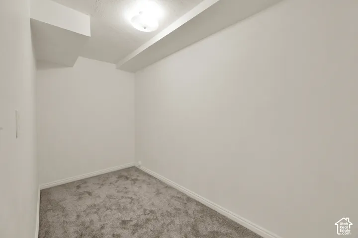 Carpeted room featuring a ceiling-mounted light fixture, white walls, and white baseboards