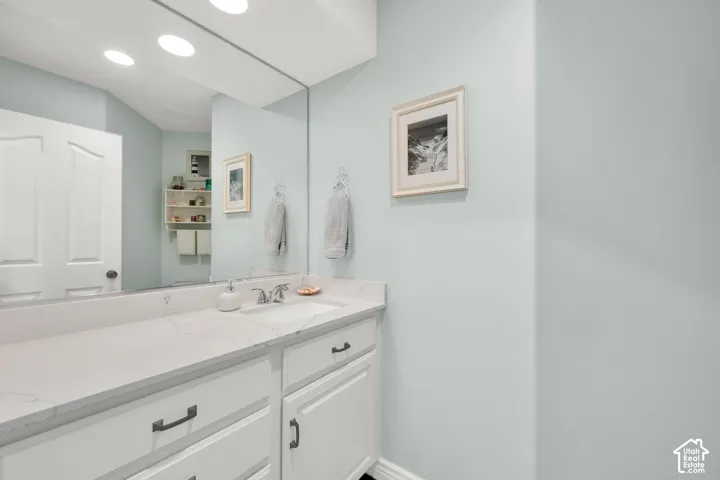 Bathroom vanity featuring a single basin, a white countertop, and white cabinetry with dark hardware