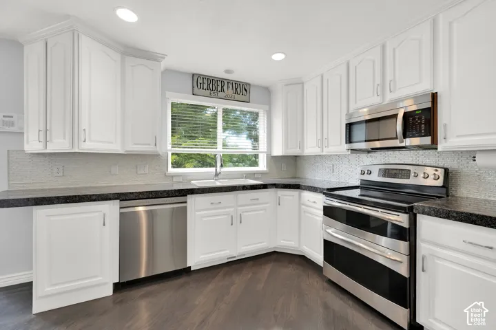 Kitchen featuring white shaker-style cabinetry, dark speckled countertops, and stainless steel appliances including a range, microwave, and dishwasher