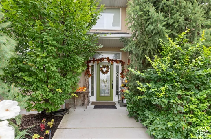 Entryway featuring a green paneled front door with sidelights, a covered porch, and a second-story window