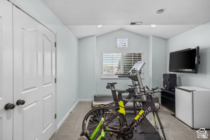 Spacious room featuring vaulted ceilings, a large window with plantation shutters, recessed lighting, and dual white paneled doors