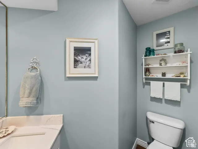 Bathroom featuring light blue wall paint, a white wall-mounted shelving unit, and a white toilet