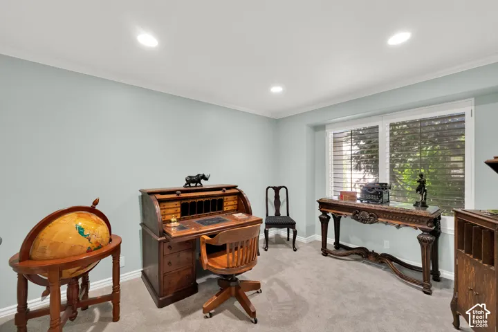 Spacious room featuring light blue walls, recessed lighting, white crown molding, a large window with white plantation shutters, and light gray carpeting