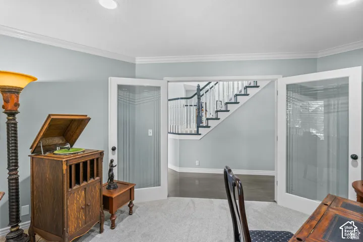 Glass-paneled double doors open to a staircase featuring white risers, dark treads, and a white and dark wood handrail