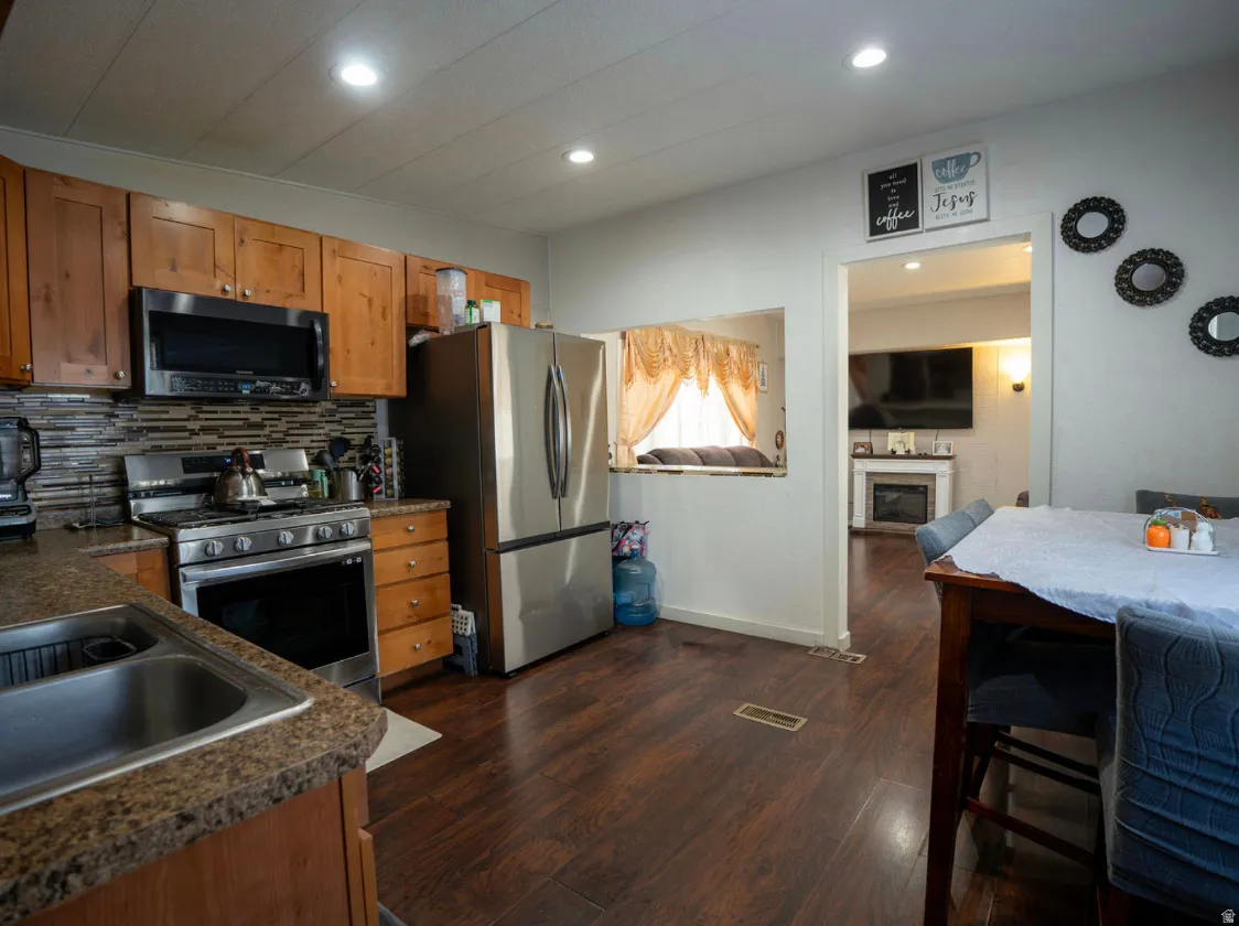 Kitchen featuring wood-finish flooring, stainless steel appliances, wood cabinetry, and recessed lighting