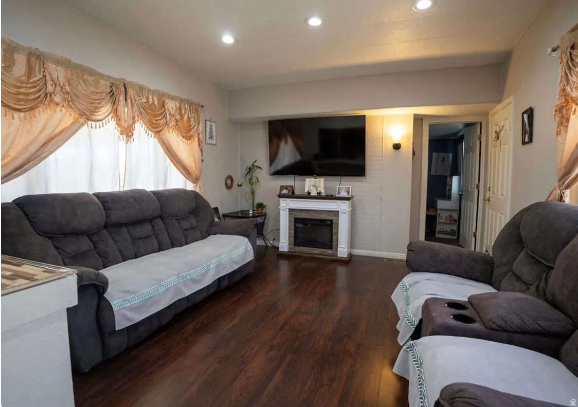 Living area featuring wood-finish flooring, recessed lighting, and a white mantel fireplace with a tile surround