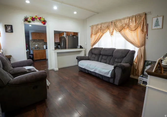 Spacious living area featuring wood-finish flooring, recessed lighting, and a pass-through window with a breakfast bar