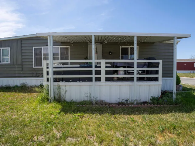 Side exterior featuring a covered porch with white railing, horizontal siding, and multiple windows