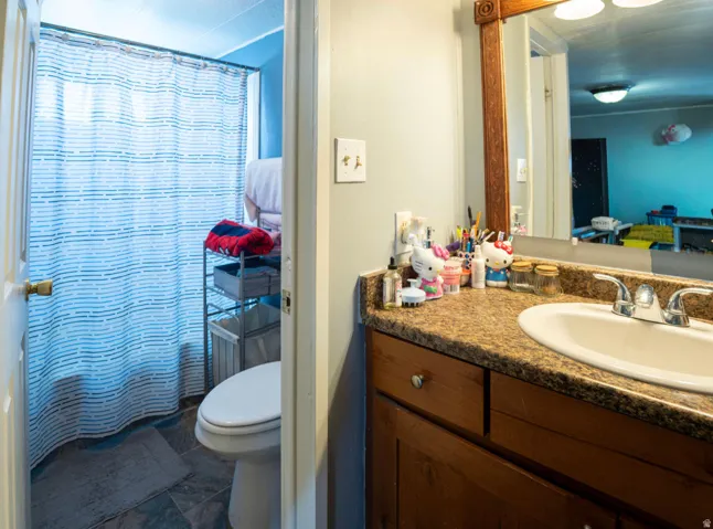Bathroom vanity featuring a built-in sink with chrome faucet, a wood-finish cabinet, and a framed mirror with integrated lighting