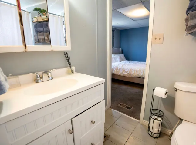 Bathroom vanity featuring an integrated sink with chrome faucet, white paneled cabinetry, and a mirrored medicine cabinet