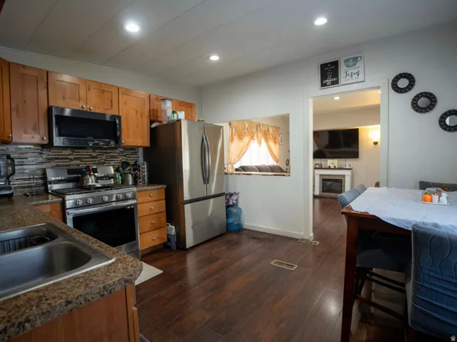 Kitchen featuring wood-finish flooring, stainless steel appliances, wood cabinetry, and recessed lighting