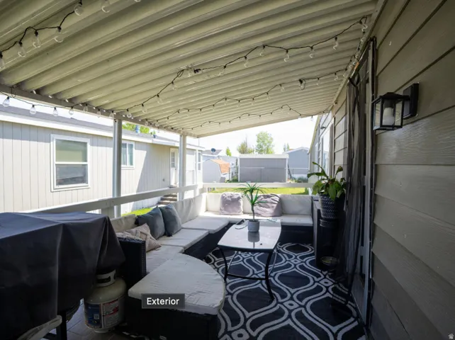 Covered patio featuring a corrugated metal roof, string lighting, and an exterior wall lantern