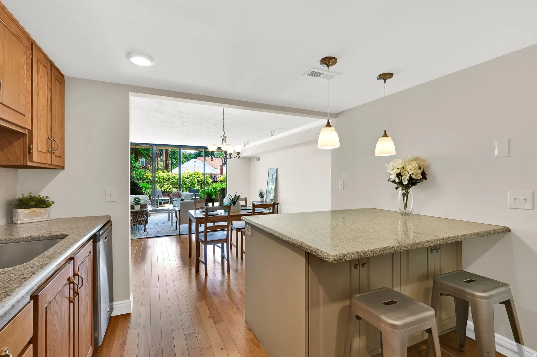 Kitchen featuring granite-style countertops, wood cabinetry, and a central island with pendant lighting