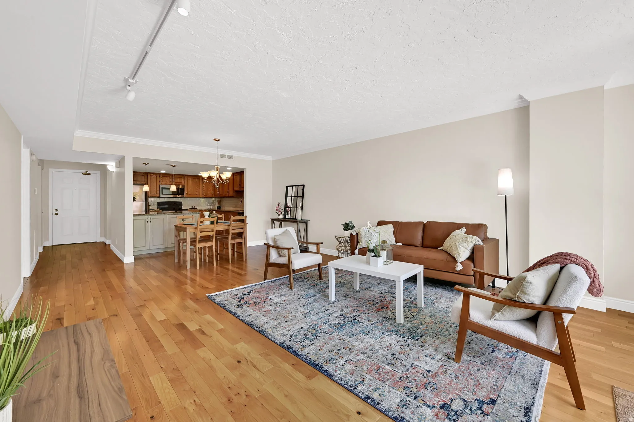 Open-concept living area featuring wood-finish flooring, neutral wall tones, and recessed track lighting