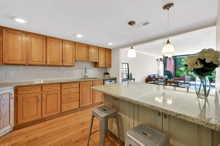 Kitchen featuring wood cabinetry, light-toned granite countertops, and a subway tile backsplash