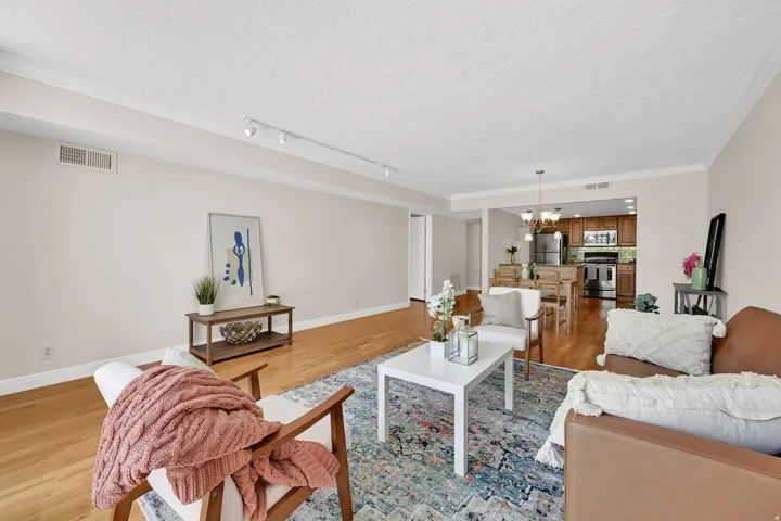 Open-concept living area featuring wood-finish flooring, recessed lighting, and crown molding