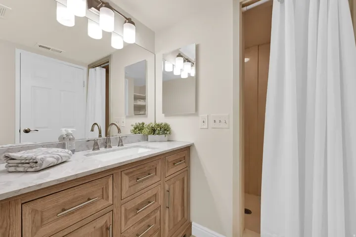 Bathroom featuring a wood-finish vanity with a light-toned countertop, an undermount sink, and brushed nickel fixtures