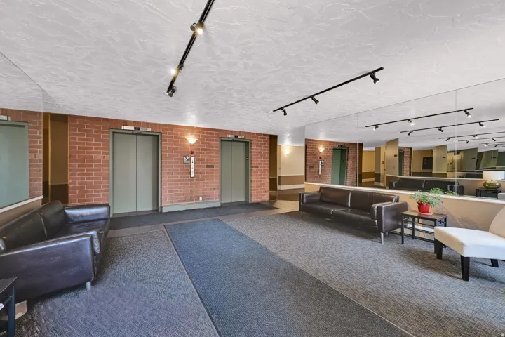 Lobby area featuring two elevators, brick accent walls, and recessed lighting