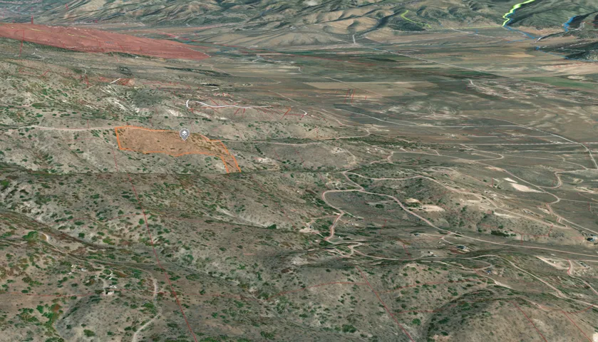 Expansive undeveloped land parcel featuring varied topography, scattered natural vegetation, and unpaved access paths