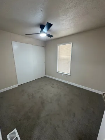 Neutral tone wall paint, dark carpet flooring, and a window with blinds