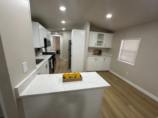 Kitchen featuring white cabinetry, light countertops, wood-finish flooring, recessed lighting, and stainless steel appliances