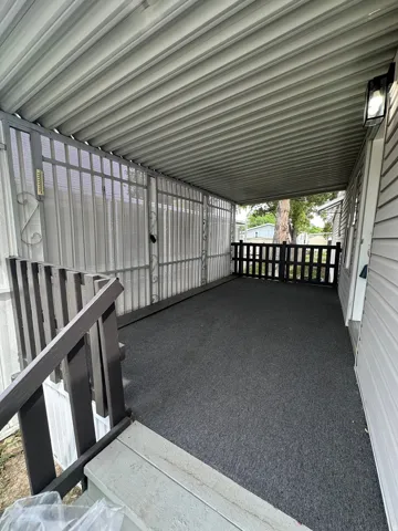 Covered porch with dark gray outdoor carpeting and white corrugated metal paneling