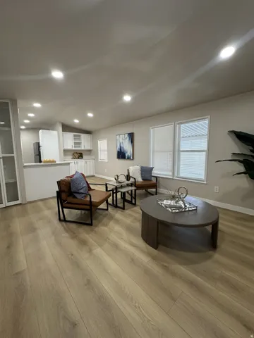 Expansive open-concept living area featuring wood-finish flooring, recessed lighting, and multiple windows