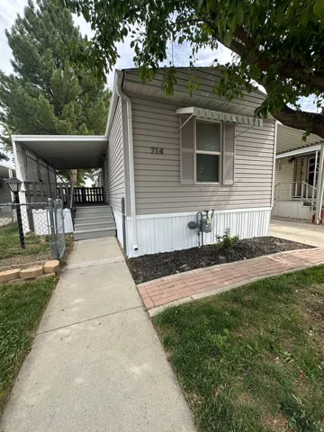 Siding exterior with a covered side porch, featuring a window awning and a concrete walkway