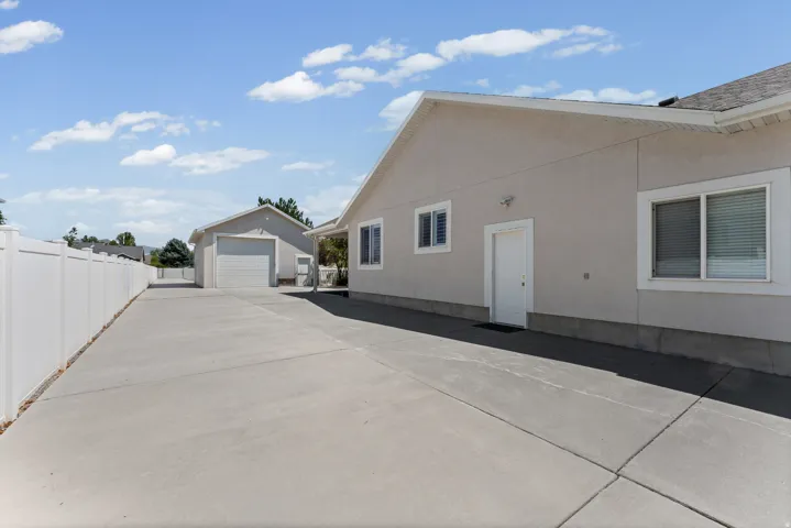 Long concrete driveway providing extensive parking capacity, bordered by a white privacy fence