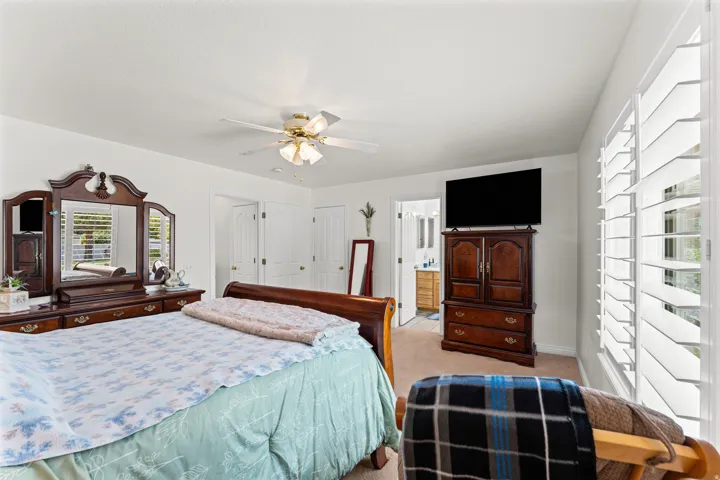 Spacious room featuring white walls, carpeting, and a ceiling fan with integrated lighting